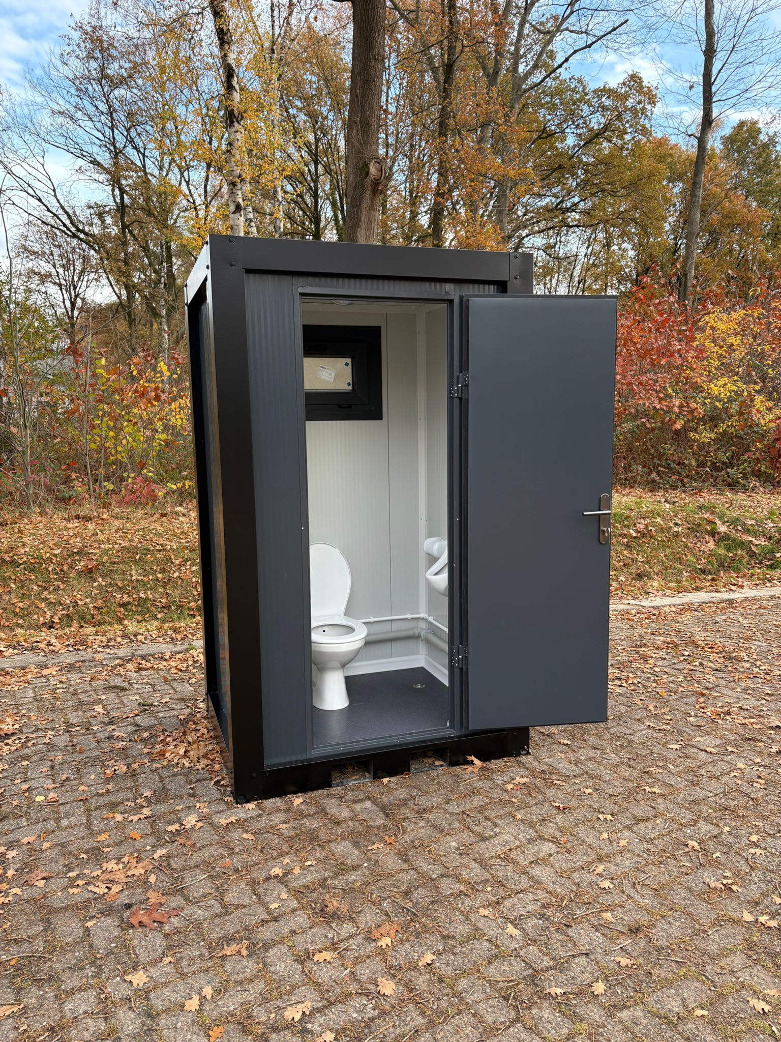 Single toilet unit met open deur en urinoir 2 Vooraanzicht single toilet unit met urinoir